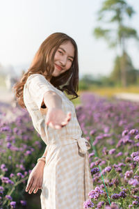 Happy woman standing by purple flower on field