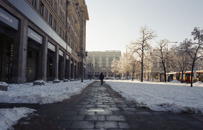 Man walking on footpath amidst buildings in city