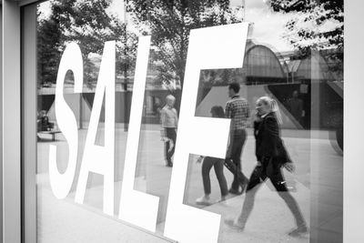 People standing by glass window in city