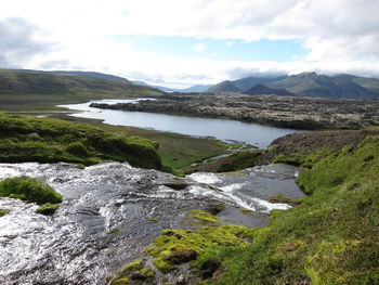 Scenic view of river and mountains against cloudy sky