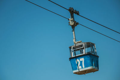 Low angle view of telephone pole against clear blue sky