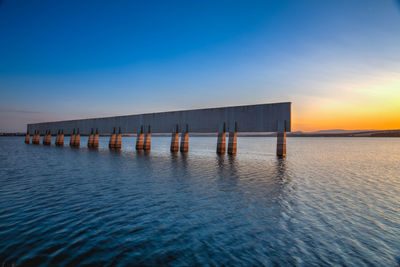 Wooden posts in sea against clear sky