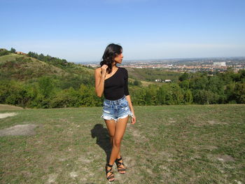 Full length of young woman standing against sky