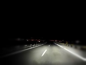 Cars on illuminated road against sky at night