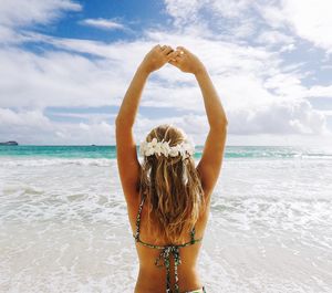 Rear view of woman standing at beach against sky