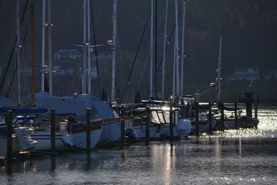 Sailboats moored on harbor during winter at night