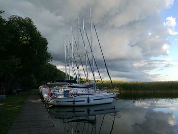 Boats moored at harbor against sky