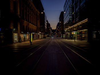 View of railroad tracks amidst buildings in city at night