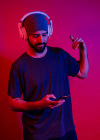 Young man using mobile phone against red background