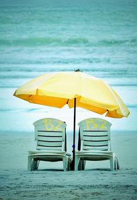 Deck chairs on beach against sea