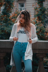 Young woman standing against trees in city