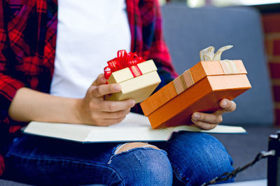 Midsection of person holding red gift boxes