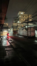 View of railroad tracks by buildings in city at night