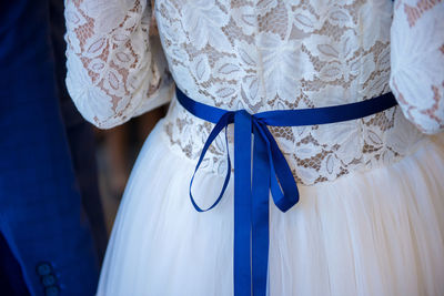 Midsection of bride with blue tied bow on waist