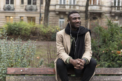 Smiling young man sitting on bench outdoors