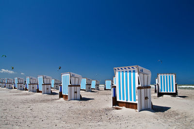 Seats on shore against clear blue sky