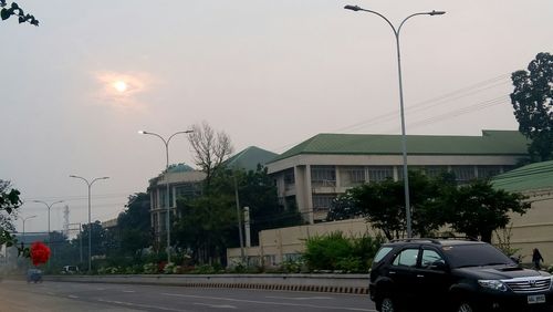 Cars on street by buildings against sky