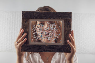 Portrait of woman holding picture frame