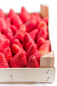 Close-up of strawberries in wooden container against white background