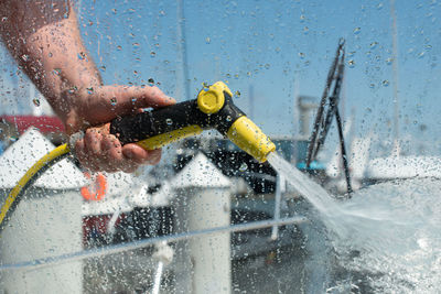 Hand holding water spray gun. man washing boat with pressure water system.  focus on water drops. 