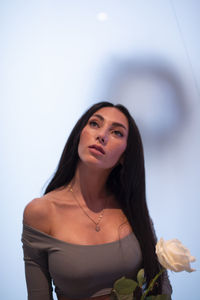 Portrait of young woman standing against white background