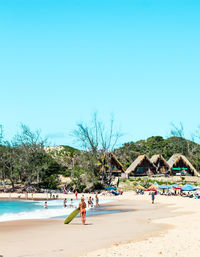 People at beach against clear blue sky