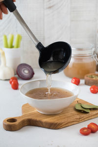 A ladle is poured with a healthy homemade bone broth into a plate.