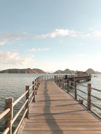 Wooden pier over sea against sky