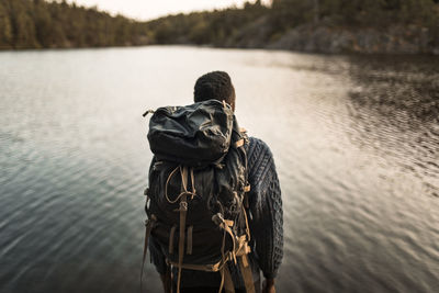 Rear view of man with backpack against lake in forest