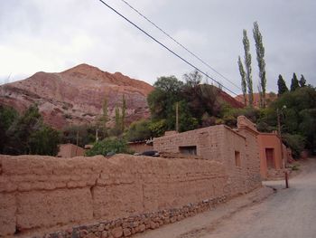 Houses by road against buildings and mountains against sky
