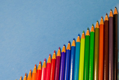 Row of multi colored pencils against blue background