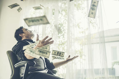 Full length of senior woman sitting against window