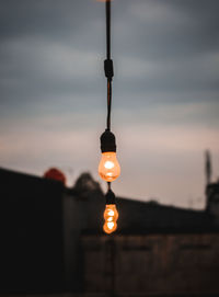 Low angle view of illuminated light bulb against sky at sunset