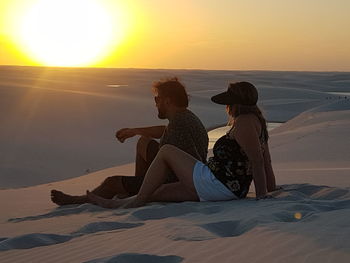 People sitting on beach looking at sunset