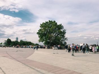 People at town square against cloudy sky