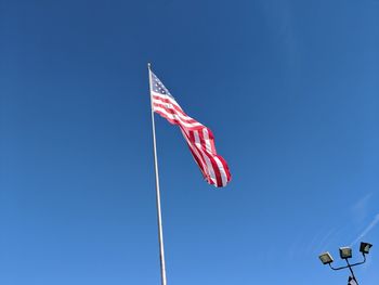 Low angle view of flag against clear blue sky