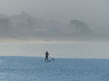 Silhouette man standing in sea against sky