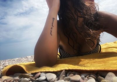 Midsection of woman at beach against sky