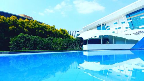 Exterior of swimming pool in front of house against sky