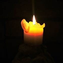 Close-up of lit candle in darkroom