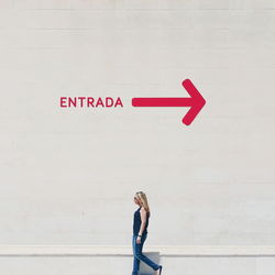 Young woman standing by text on wall