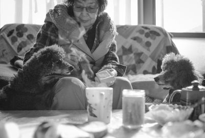 Senior woman sitting on sofa with dog at home