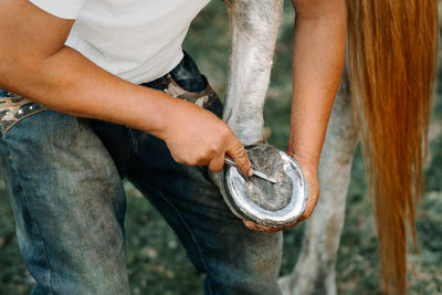 Midsection of man cleaning horseshoe