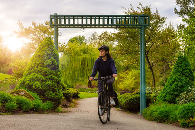 Full length of man riding bicycle on plants