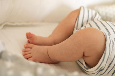 Low section of baby lying on bed