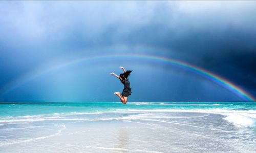 Silhouette of woman jumping on beach