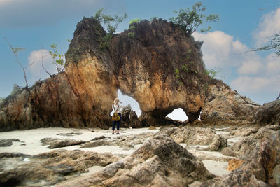 Rear view of man on rock formation against sky