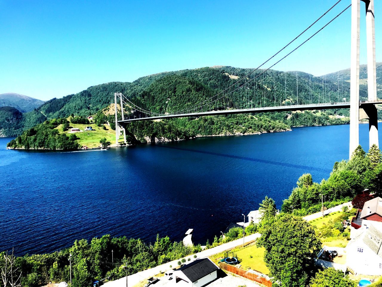 mountain, water, sky, tree, architecture, plant, nature, built structure, scenics - nature, day, blue, clear sky, transportation, no people, beauty in nature, connection, river, building exterior, bridge, bridge - man made structure, outdoors, mountain range, bay