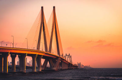 Bridge over river against sky during sunset