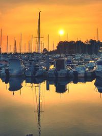 Sailboats moored at harbor during sunset